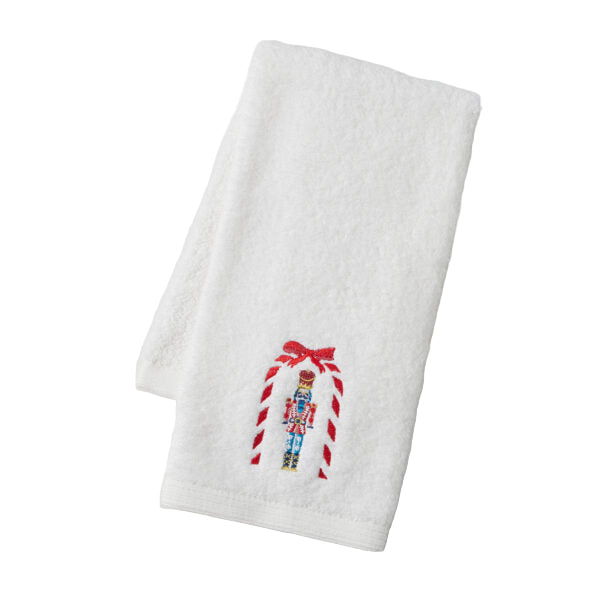 White towel with embroidered candy cane and nutcracker design on a light gray background