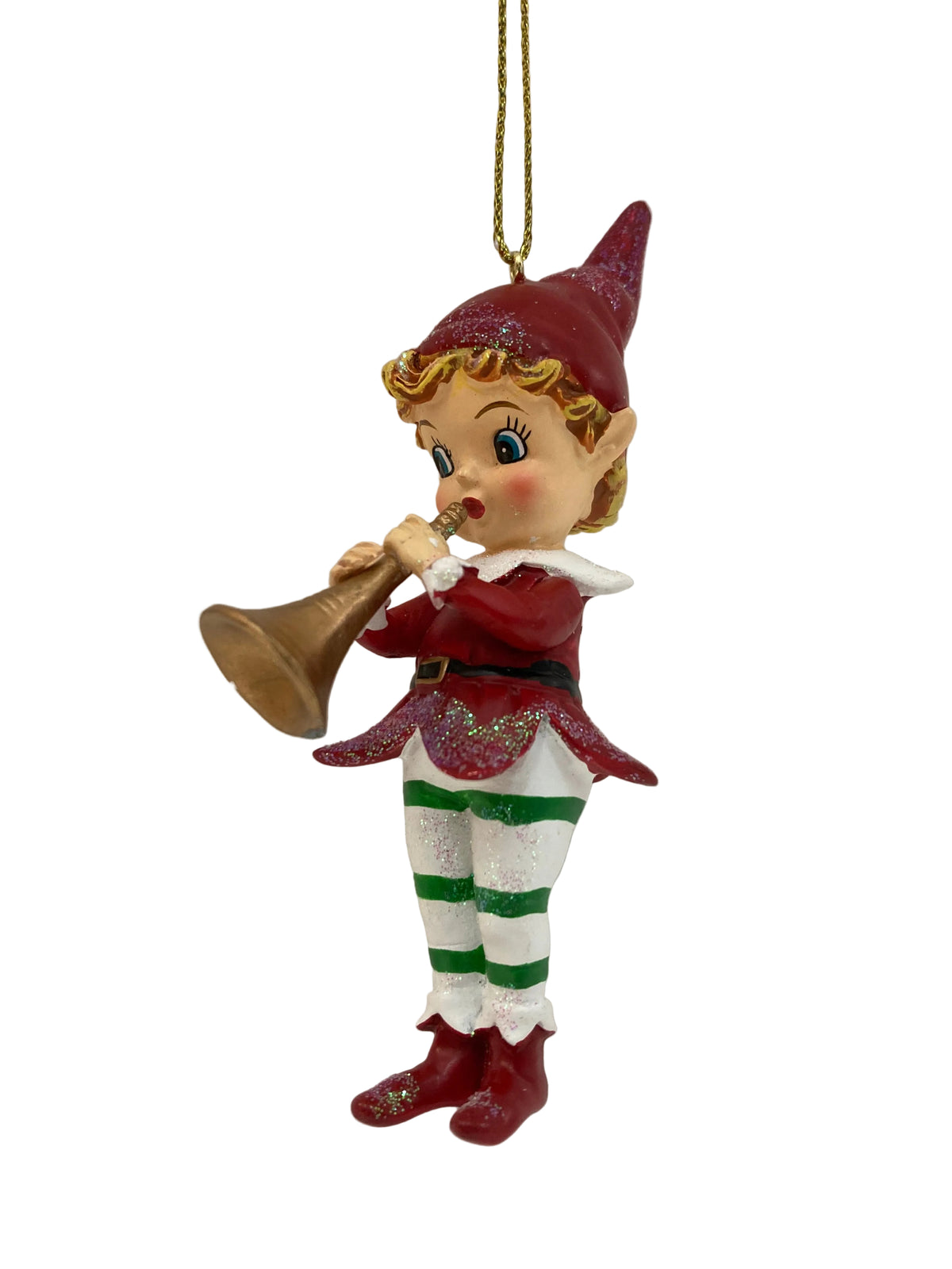 A Christmas elf ornament hanging from a gold string, featuring a child-like elf in a red hat and red outfit playing a gold trumpet, with green-and-white striped socks and red boots, set against a plain light background.