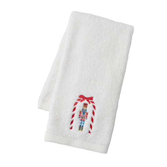 White towel with embroidered candy cane and nutcracker design on a light gray background
